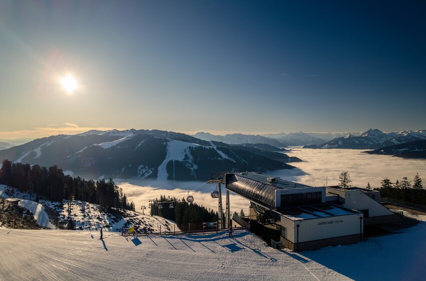Gabühelbahn am Hochkönig mit Gondeln und Skipiste vor verschneiten Bergen und einem dichten Nebelmeer im Tal | © Hochkönig Bergbahnen GmbH