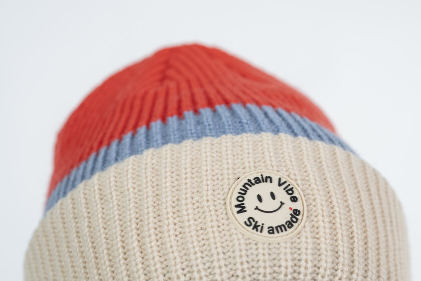 Beige, rote und blaue Mütze mit rundem Mountain Vibe Patch und Ski amadé Logo | © Ski amadé GmbH / Lorenz Masser