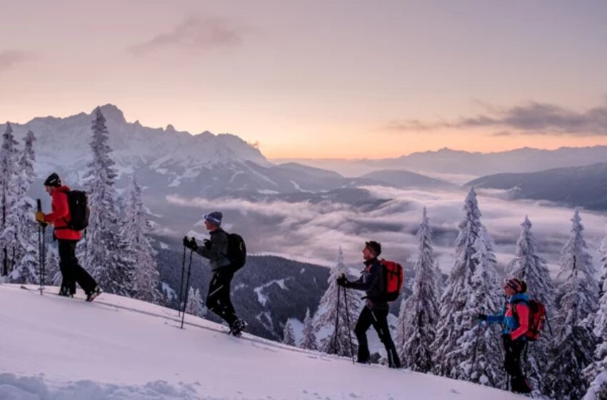 Vier Skitourengeher steigen bei Sonnenuntergang durch verschneiten Hang im Gebirge. | © Ski amadé GmbH